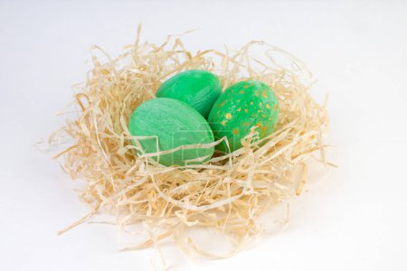 Téléchargez les photos : Bonne carte de Pâques. Œufs brillants colorés dans un nid isolé sur un fond blanc. Espace de copie pour le texte - en image libre de droit
