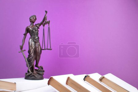 Téléchargez les photos : Concept de droit - livre de droit ouvert, marteau du juge, échelles, statue de Themis sur la table dans une salle d'audience ou un bureau d'application de la loi. Table en bois, fond violet - en image libre de droit