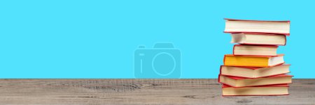 Photo for Composition with hardback books on wooden deck table and blue background. Books stacking. Back to school. Copy Space. Education background - Royalty Free Image