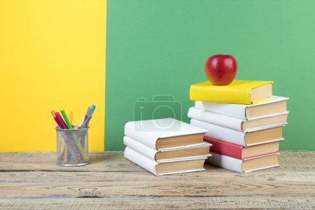 Téléchargez les photos : Des livres empilés. Livres sur table en bois et fond vert jaune. Je retourne à l'école. Espace de copie pour texte publicitaire - en image libre de droit