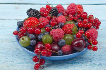 Photo for Various summer Fresh berries in a bowl on rustic wooden table. Antioxidants, detox diet, organic fruits - Royalty Free Image