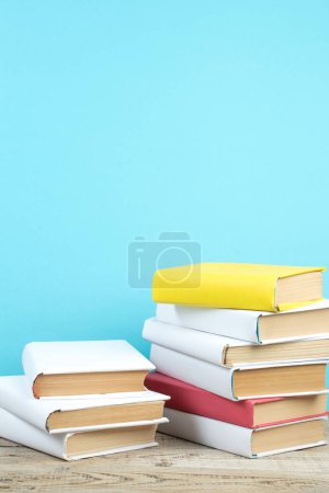 Téléchargez les photos : Des livres empilés. Livres sur table en bois et fond bleu. Je retourne à l'école. Espace de copie pour texte publicitaire - en image libre de droit