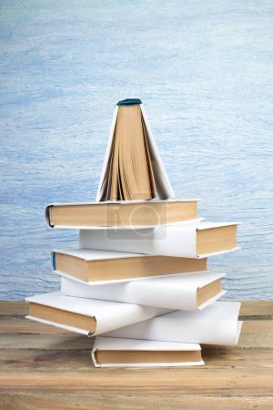 Photo for Stack of books in the shape of a Christmas tree on a blue background. Back to school. Education. Copy space for text - Royalty Free Image