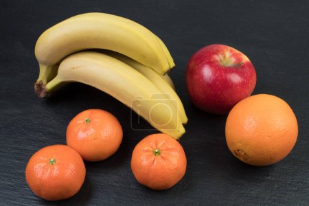 Foto de Frutas. Plátanos, manzanas, naranjas mandarinas sobre fondo negro - Imagen libre de derechos