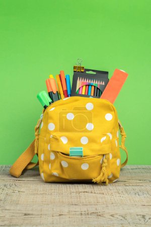 Photo for Backpack with different colorful stationery on table. White background. Back to school. - Royalty Free Image