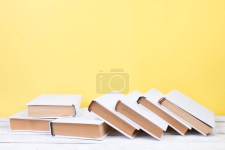 Photo for Open books, hardback colorful books on wooden table. yellow background. Back to school. Copy space for text. Education business concept - Royalty Free Image
