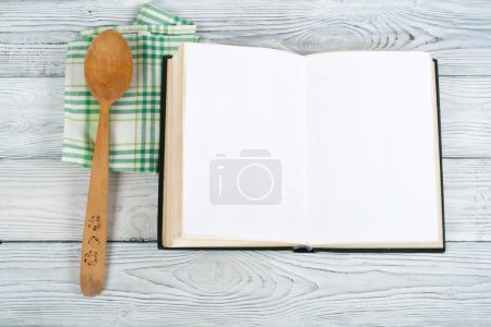 Téléchargez les photos : Recette cuisine livre blanc sur fond bois, cuillère, rouleau à pâtisserie, nappe à carreaux
. - en image libre de droit