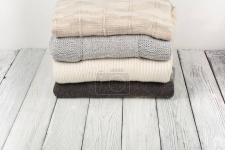 Photo for Knitted wool sweaters. Pile of knitted winter clothes on wooden background, sweaters, knitwear, space for text - Royalty Free Image