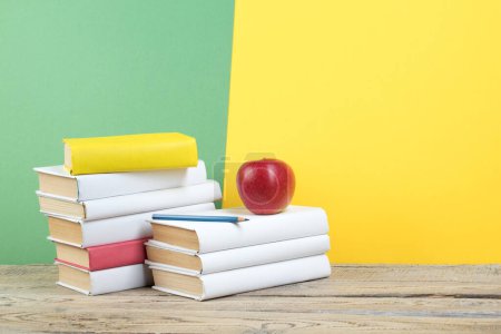 Photo for Books stacking. Books on wooden table and green, yellow background. Back to school. Copy space for ad text - Royalty Free Image