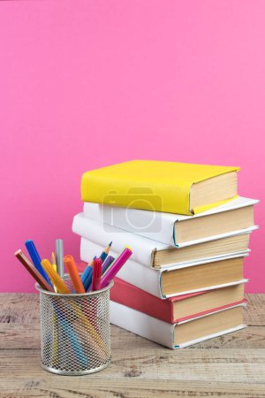 Foto de Libros apilados. Libros sobre mesa de madera y fondo rosa. De vuelta a la escuela. Copiar espacio para texto del anuncio - Imagen libre de derechos