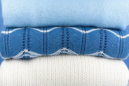 Photo for Knitted wool sweaters. Pile of knitted winter, autumn clothes on blue, wooden background, sweaters, knitwear, space for text - Royalty Free Image