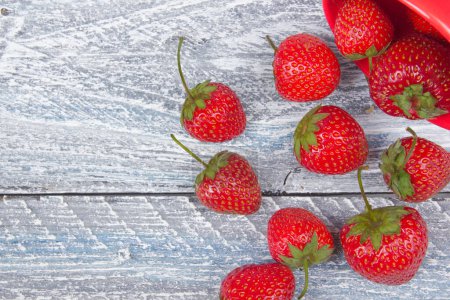 Photo for Strawberries on wooden table background, spilled from a spice jar. Antioxidants, detox diet, organic fruits - Royalty Free Image