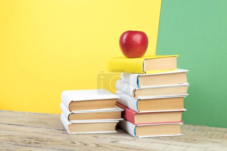 Foto de Libros apilados. Libros sobre mesa de madera y fondo verde y amarillo. De vuelta a la escuela. Copiar espacio para texto del anuncio - Imagen libre de derechos