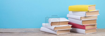 Foto de Libros apilados. Libros sobre mesa de madera y fondo azul. De vuelta a la escuela. Copiar espacio para texto del anuncio - Imagen libre de derechos