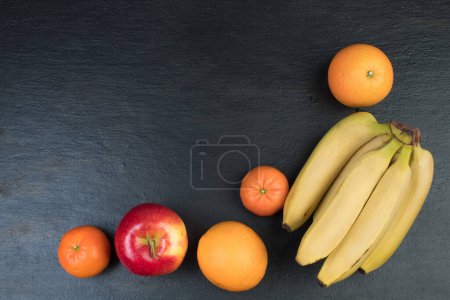 Foto de Frutas. Plátanos, manzanas, naranjas mandarinas sobre fondo negro - Imagen libre de derechos