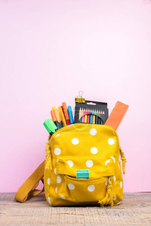 Photo for Backpack with different colorful stationery on table. Pink background. Back to school. - Royalty Free Image