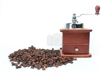 Photo for A pile of coffee beans on a white background and a coffee grinder. Top view - Royalty Free Image