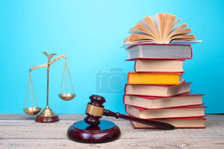 Photo for Law concept - Open law book, Judge's gavel, scales, Themis statue on table in a courtroom or law enforcement office. Wooden table, blue background. - Royalty Free Image