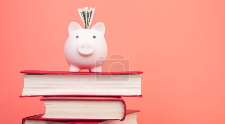 Photo for Piggy bank in glasses and books on Orange background. open book. Tuition payment. Brainwork - Royalty Free Image