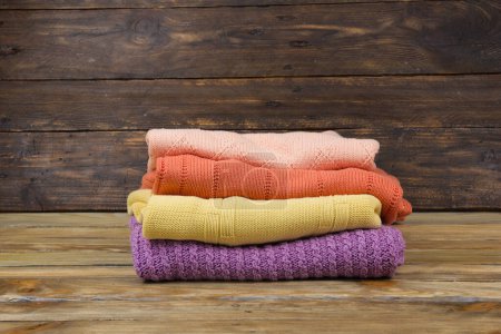 Téléchargez les photos : Pull en laine tricotée. Pile de vêtements d'été tricotés sur fond bois, pulls, tricots, espace pour le texte - en image libre de droit