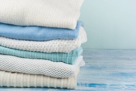 Photo for Knitted wool sweaters. Pile of knitted winter clothes on wooden background, sweaters, knitwear, space for text - Royalty Free Image