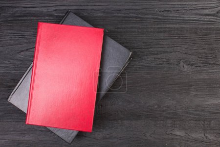 Téléchargez les photos : Livres rouges et noirs sur un bureau en bois noir. vue de dessus - en image libre de droit