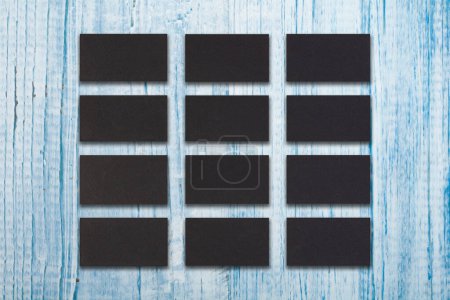 Foto de Mockup de las pilas horizontales negras de las tarjetas de visita arregladas en filas en el fondo azul de madera - Imagen libre de derechos