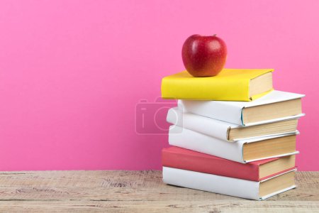 Téléchargez les photos : Des livres empilés. Livres sur table en bois et fond rose. Je retourne à l'école. Espace de copie pour texte publicitaire - en image libre de droit