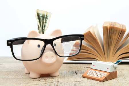Photo for Piggy bank in glasses and books on white background. open book. Tuition payment. Brainwork. Typewriter. The concept of literary creativity. - Royalty Free Image