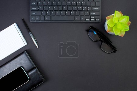 Téléchargez les photos : Table de bureau noir avec ordinateur, stylo et une tasse de café, beaucoup de choses. Vue supérieure avec espace de copie - en image libre de droit