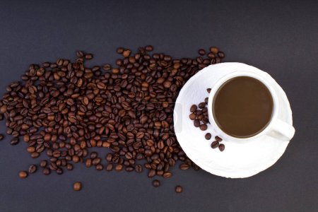 Téléchargez les photos : Une pile de grains de café, une tasse de café blanche sur un fond sombre. Vue du dessus - en image libre de droit