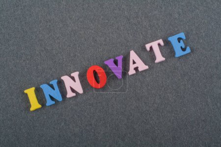 INNOVATE word on black board background composed from colorful abc alphabet block wooden letters, copy space for ad text. Learning english concept