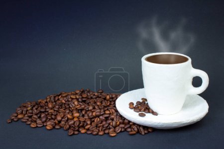 Foto de Una pila de granos de café, una taza de café blanco sobre un fondo oscuro. Vista frontal - Imagen libre de derechos