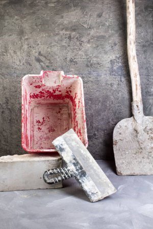 Téléchargez les photos : Outils de construction vieille, pelle sale, seau rouge, briques sur le fond de béton gris. Espace de copie. Vue du dessus - en image libre de droit
