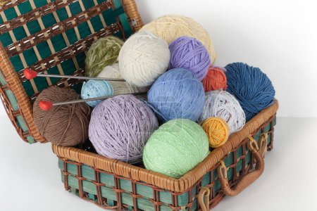Foto de Bola de lana, agujas y suéter de lana con radios para tejer a mano en canasta sobre mesa de madera - Imagen libre de derechos