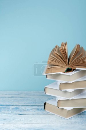 Photo for Book stacking. Open book, hardback books on wooden table and blue background. Back to school. Copy space for text - Royalty Free Image