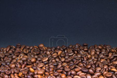 Foto de Granos de café tostados marrón primer plano sobre fondo oscuro - Imagen libre de derechos