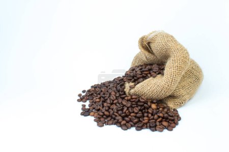 Foto de Bolsas abiertas de arpillera esparcidas con granos de café enteros sobre un fondo blanco - Imagen libre de derechos