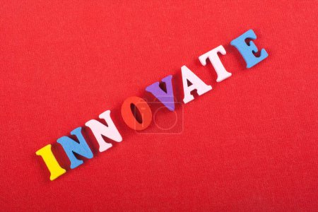 INNOVATE word on red background composed from colorful abc alphabet block wooden letters, copy space for ad text. Learning english concept