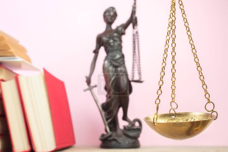 Rechtskonzept - Offenes Gesetzbuch, Richtergabel, Waage, Themis Statue auf dem Tisch im Gerichtssaal oder in der Strafverfolgungsbehörde. Holztisch, rosa Hintergrund.