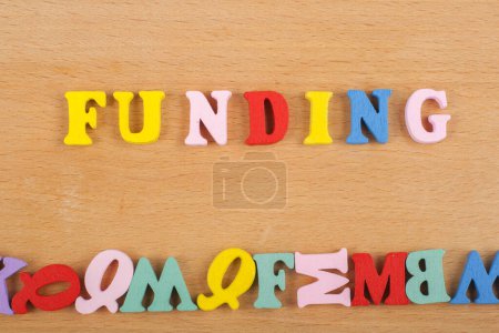 FUNDING word on wooden background composed from colorful abc alphabet block wooden letters, copy space for ad text. Learning english concept