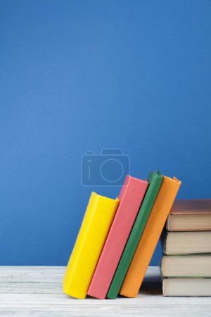 Téléchargez les photos : Empilement de livres. Livre ouvert, livres à dos dur sur table en bois et fond bleu. Je retourne à l'école. Espace de copie pour le texte - en image libre de droit