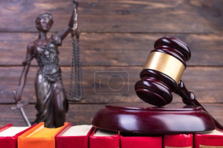 Rechtskonzept - Offenes Gesetzbuch, Richtergabel, Waage, Themis Statue auf dem Tisch im Gerichtssaal oder in der Strafverfolgungsbehörde. hölzerner Hintergrund.