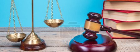 Rechtskonzept - Offenes Gesetzbuch, Richtergabel, Waage, Themis Statue auf dem Tisch im Gerichtssaal oder in der Strafverfolgungsbehörde. Holztisch, blauer Hintergrund.