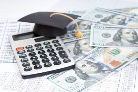 Small graduation cap on calculator, assorted cash