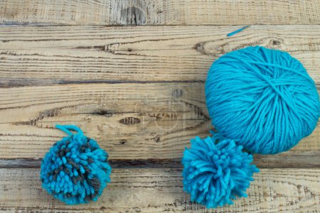 Skein of blue threads for knitting on a wooden background. pompon. fluffy soft pompon made of yarn