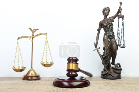 Rechtskonzept - Offenes Gesetzbuch, Richtergabel, Waage, Themis Statue auf dem Tisch im Gerichtssaal oder in der Strafverfolgungsbehörde. Holztisch, weißer Hintergrund.