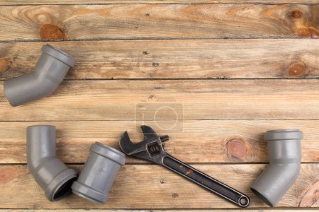 Photo for Fittings, pipe, valves, plastic pipe for water, adjustable wrench on the wooden background. Top view. Copy space for text - Royalty Free Image