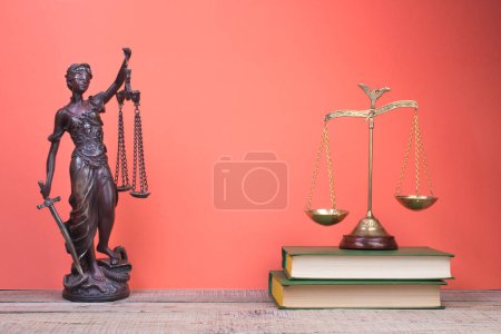 Photo for Law concept - Open law book, Judge's gavel, scales, Themis statue on table in a courtroom or law enforcement office. Wooden table, red background. - Royalty Free Image