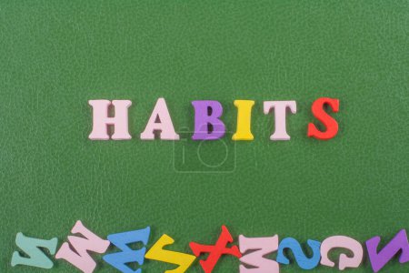 HABITS word on green background composed from colorful abc alphabet block wooden letters, copy space for ad text. Learning english concept